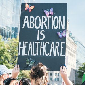 a woman holding up a sign that says abortion is healthcare